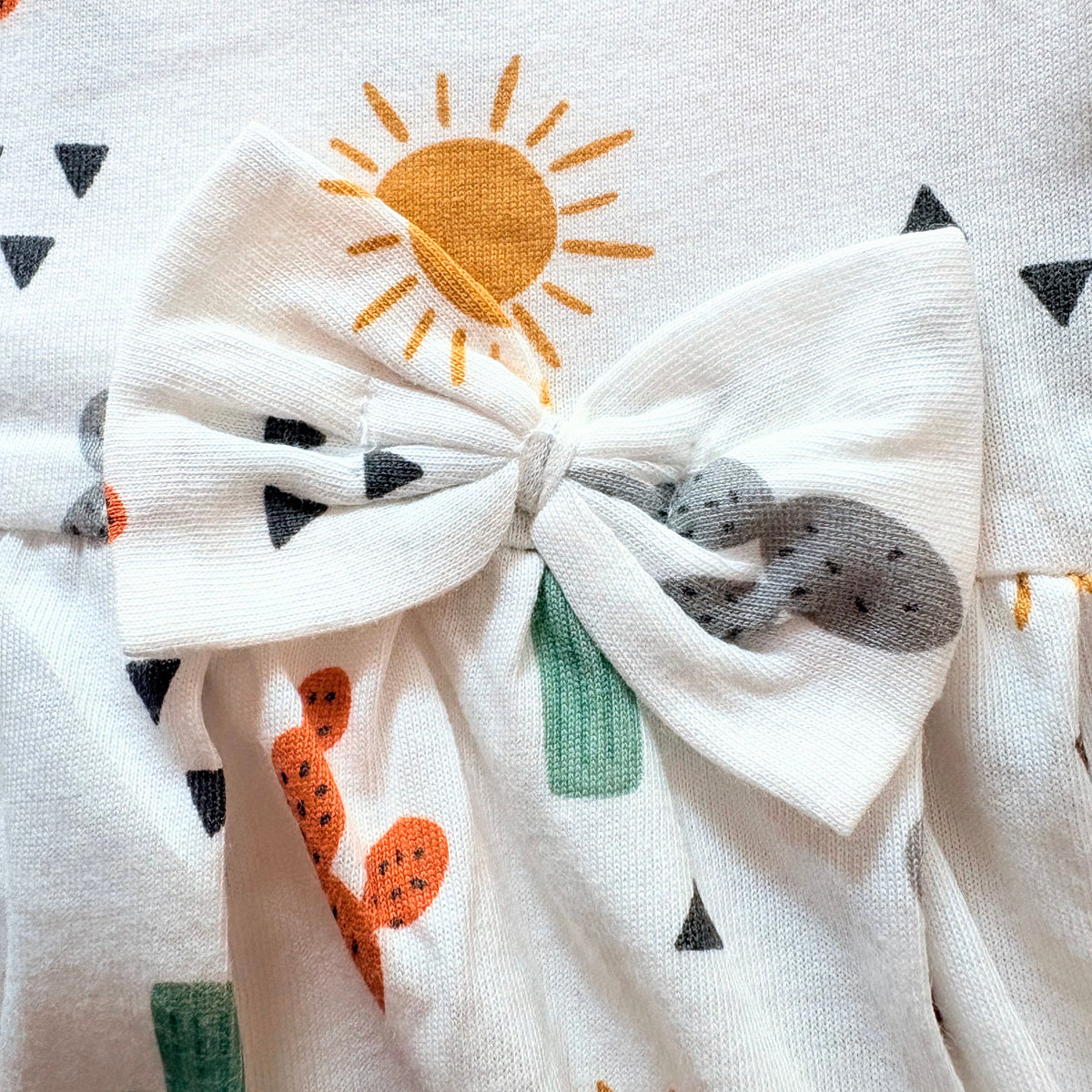Close up of the sun print and bow on the Sunny Cactus Cotton Frock.